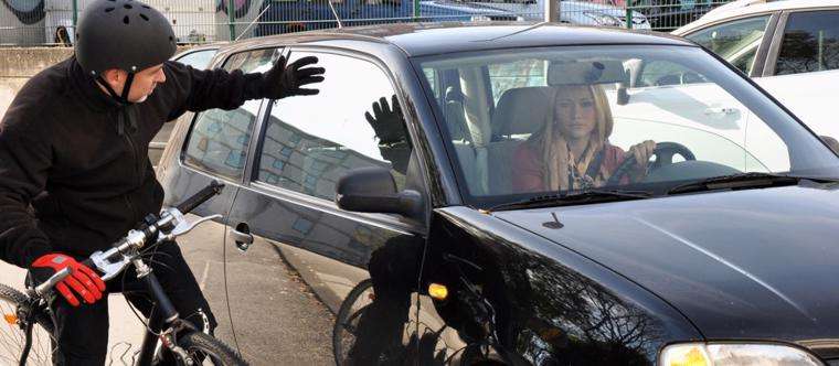 This image shows a woman nearly hitting a bike rider due to negligence.