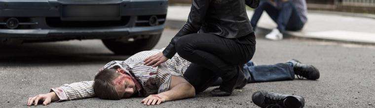 This image shows a man injured on the road after being hit by a car.