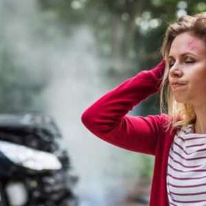 A woman with her hands on her head after a car accident.