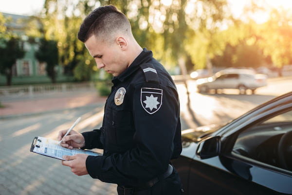 An officer writes a police report after a Suwanee car accident.