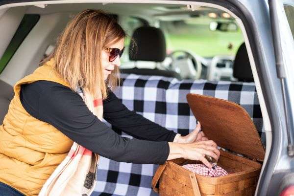 A woman packing a picnic basket for a tailgate party