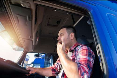 A tired truck driver yawning