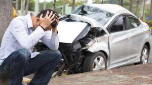 A man holding his head in his hands following a car accident.
