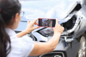 Woman Taking Photos of Damaged Car After Accident
