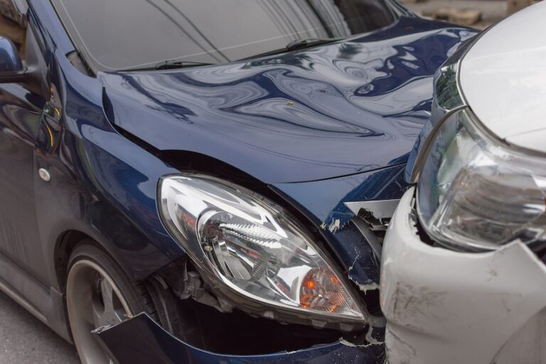 A close-up of crumpled front-end damage from rental car accidents showing a crushed hood and broken headlight between two vehicles in Georgia.