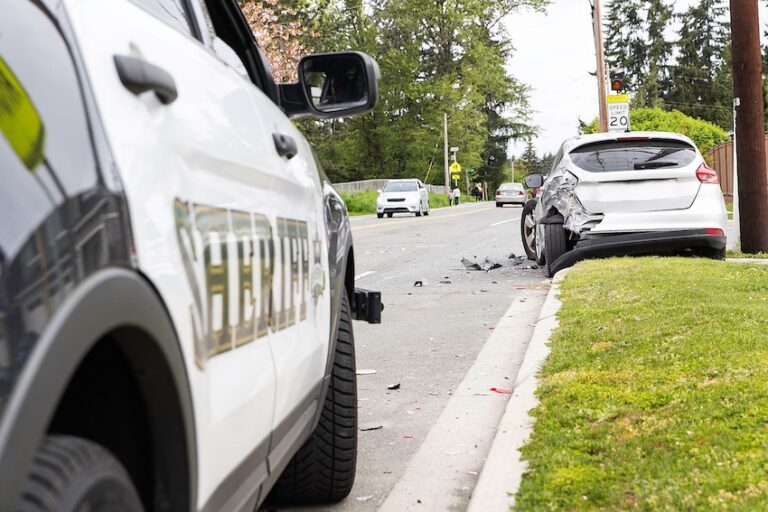 A sheriff patrol vehicle is parked behind a damaged white car on a residential street enforcing move over law safety protocols during auto accidents in Georgia.