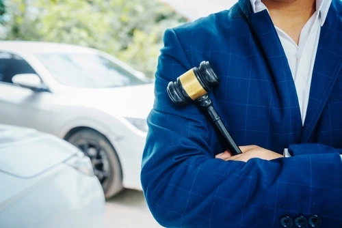 Accident lawyer in Athens standing beside a car and holding a judge's gavel
