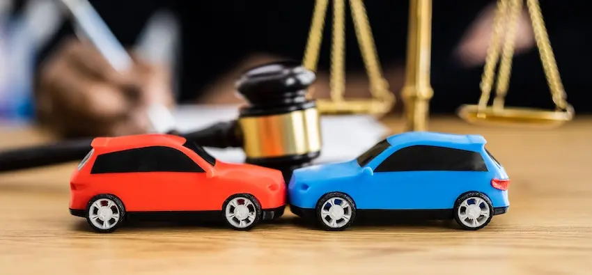 Two toy cars in front of a gavel and scales of justice represent airbag accident litigation and legal proceedings at The Weinstein Firm within Georgia.