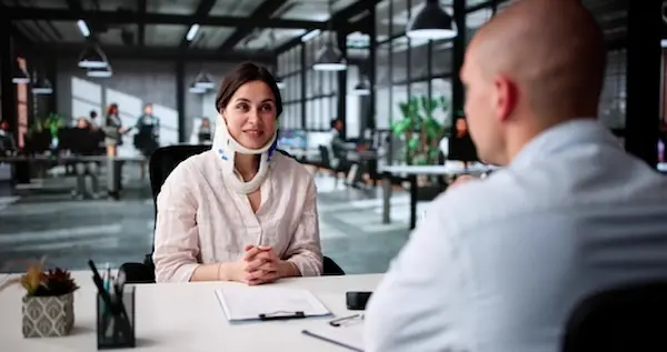 The Weinstein Firm's Georgia personal injury law firm consulting with an injured female client wearing a neck brace.