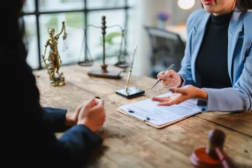 Personal Injury lawyer speaking with a client at a desk that has legal documents on it.