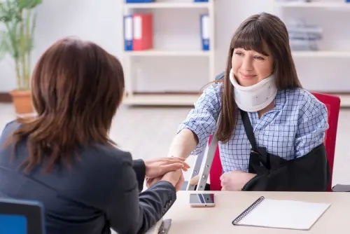 A Sandy Springs Uber accident lawyer is consulting with a rideshare victim wearing a neck brace at The Weinstein Firm.