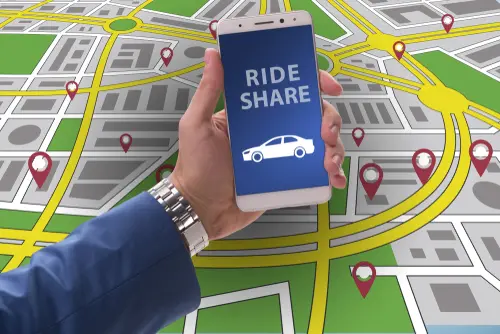 A man holding a phone displaying a rideshare app to represent a rideshare accident lawyer reviewing evidence