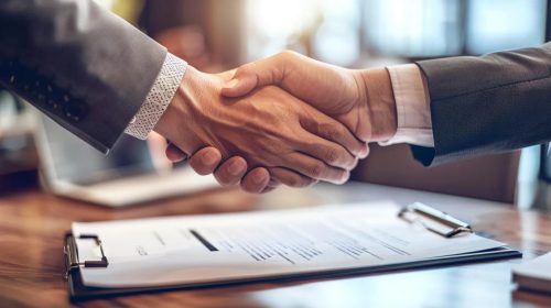 Image of two hands shaking over a document, symbolizing settlement negotiation and agreement.